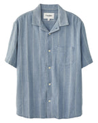 A striped seersucker short-sleeved shirt in blue and white, with a camp collar and corozo buttons, displayed on a white background.