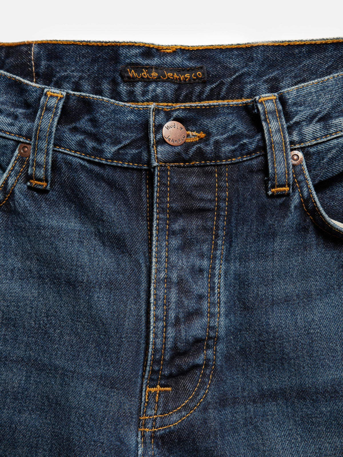 Nudie Jeans Steady Eddie II Blue Soil, close-up of the button fly showing the copper button and tobacco-colored stitching.