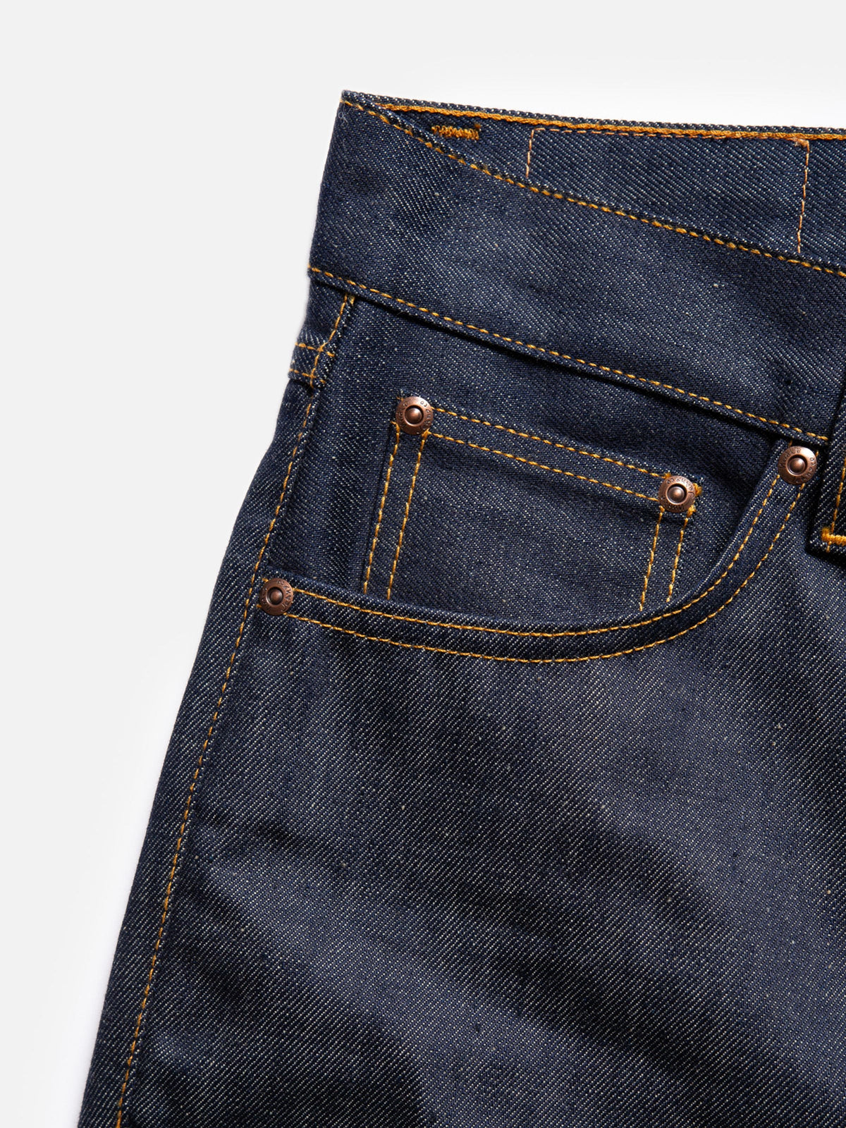 Nudie Jeans Gritty Jackson Dry Old, close-up of the front pocket, showing rigid denim, tobacco stitching, and copper rivets.