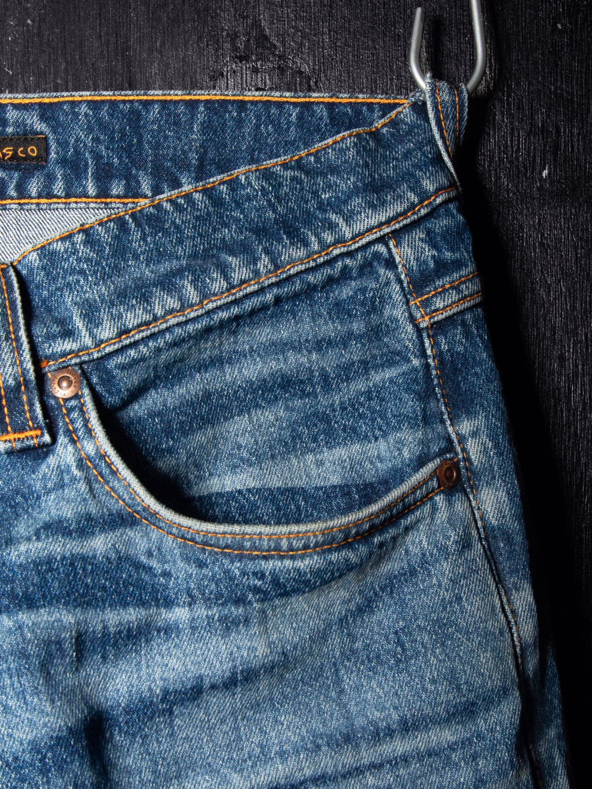 Nudie Jeans Solid Ollie Life Tracks, close-up of the front pocket showing the mid-blue wash, worn texture, and whiskering.