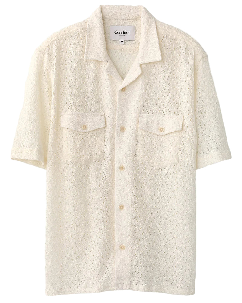A white short-sleeved button-up shirt with floral lace pattern, featuring a camp collar and two chest pockets.
